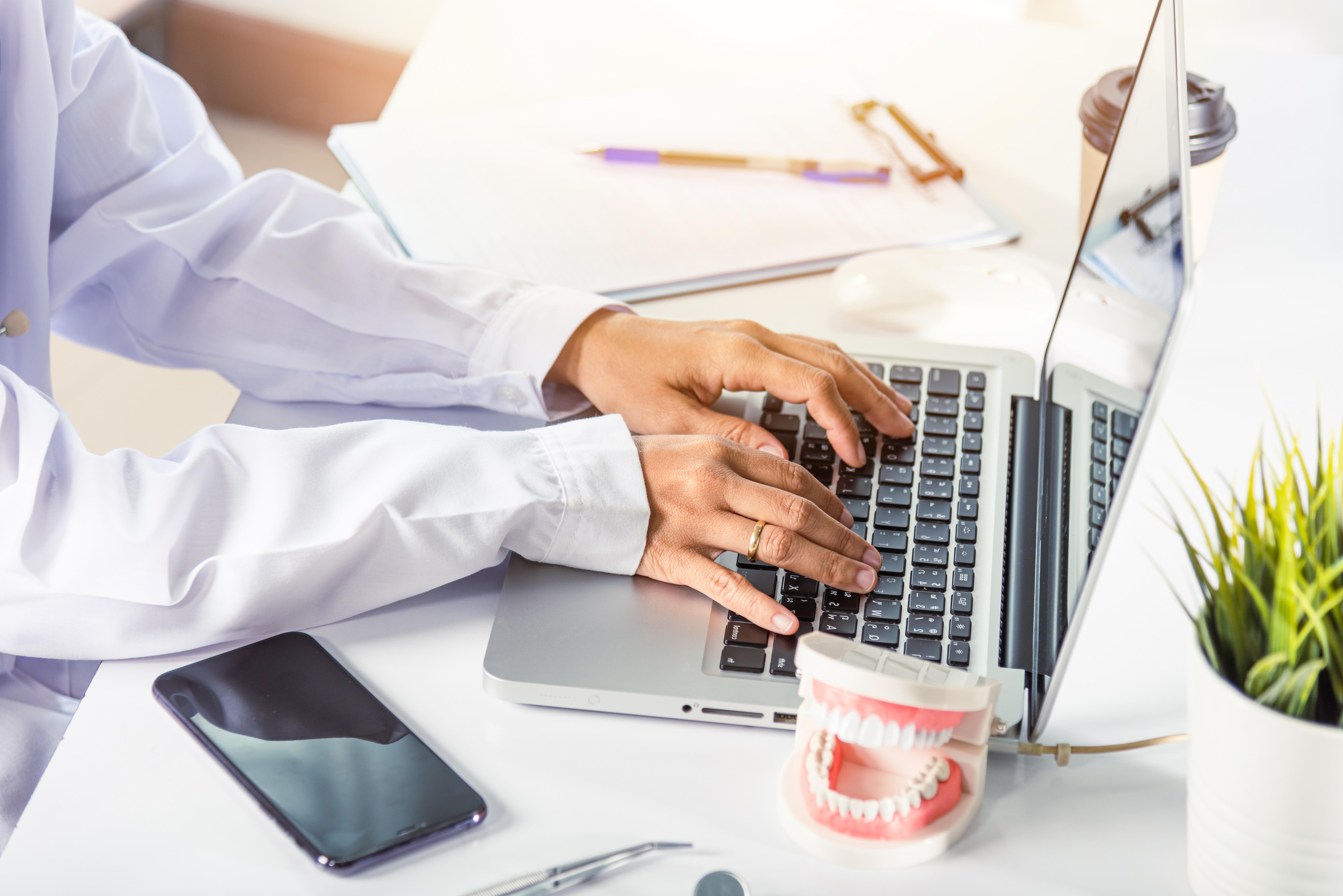 Dental professional in uniform on laptop